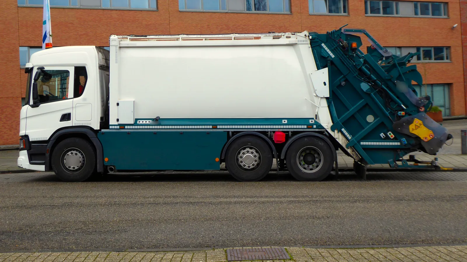 Camión recolector de basura con compactador de carga trasera estacionado en una calle